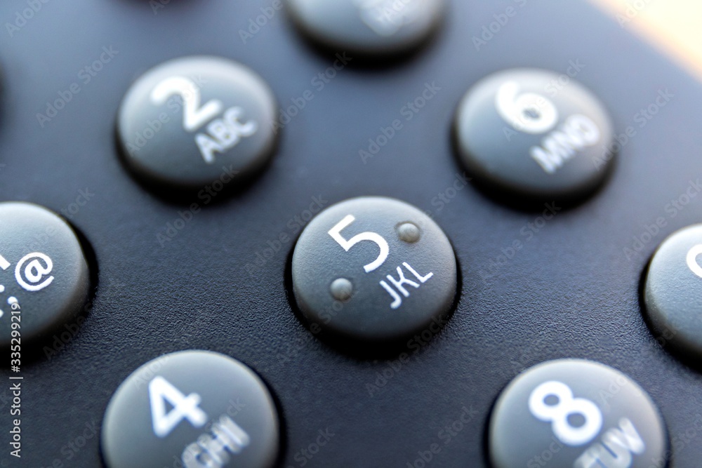 A close up portrait of the numeric buttons of a television remote control. The button with number 5 is in the center, surounded by the others of its kind to use to change the channel. A close up portrait of the numeric buttons of a television remote control. The button with number 5 is in the center, surounded by the others of its kind to use to change the channel.