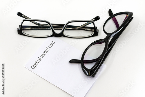 Optical record card with two pais of black glasses with lenses isolated against a plain white background