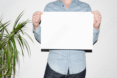 A3 Poster Mock-Up - Man in a denim shirt holding a poster on a white background. Hipster Aesthetic