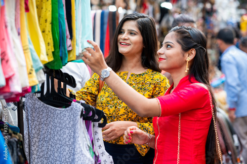 Two Beautiful brunette Indian girls looking for new clothes in market for festival season