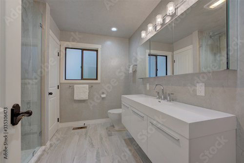 New modern bathroom interior grey venetian plaster  grey tiles  shower with glass walls  slick white shiny venity.