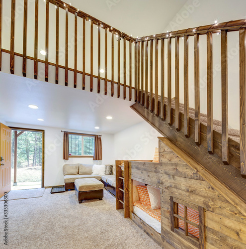 Living room interior with beige sofa, natural touches, custom build wooden bunk bed, tall ceiling with loft.