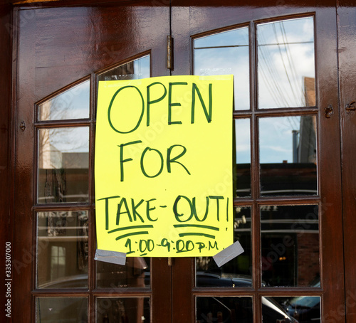 Open for take out poster taped on windows of restaurant photo