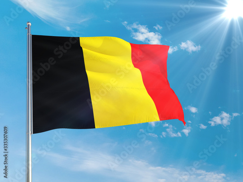 Belgium national flag waving in the wind against deep blue sky. High quality fabric. International relations concept.