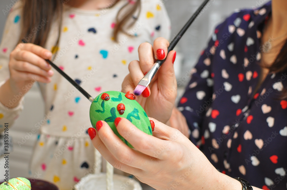 Mom and daughter painting Easter eggs. Mom and child smiling and play with Easter eggs. Happy family Mom and daughter painting Easter eggs. Mom and child smiling and play with Easter eggs. Happy family