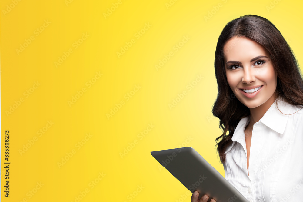 Happy smiling beautiful young brunette businesswoman using no-name tablet pc, over orange yellow color background, with copy space for some slogan or text. Success in business concept. Happy smiling beautiful young brunette businesswoman using no-name tablet pc, over orange yellow color background, with copy space for some slogan or text. Success in business concept.