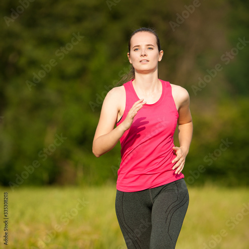 Beautiful young woman workout outdoor runs across meadow in early summer © Samo Trebizan