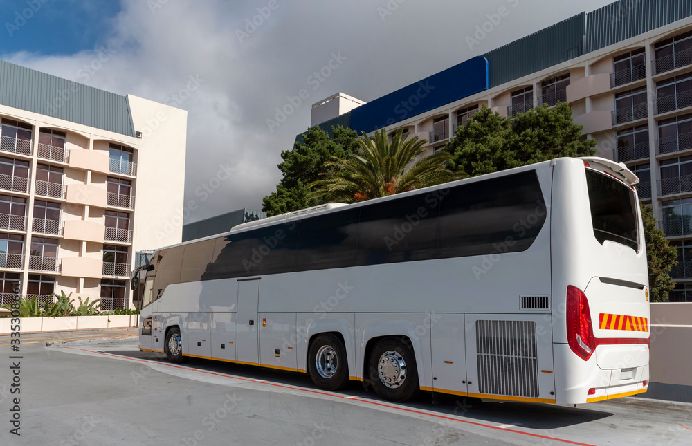 Naklejka premium Cape Town, South Africa. 2019. A white tourist bus at a hotel overlooked by accomodation rooms.