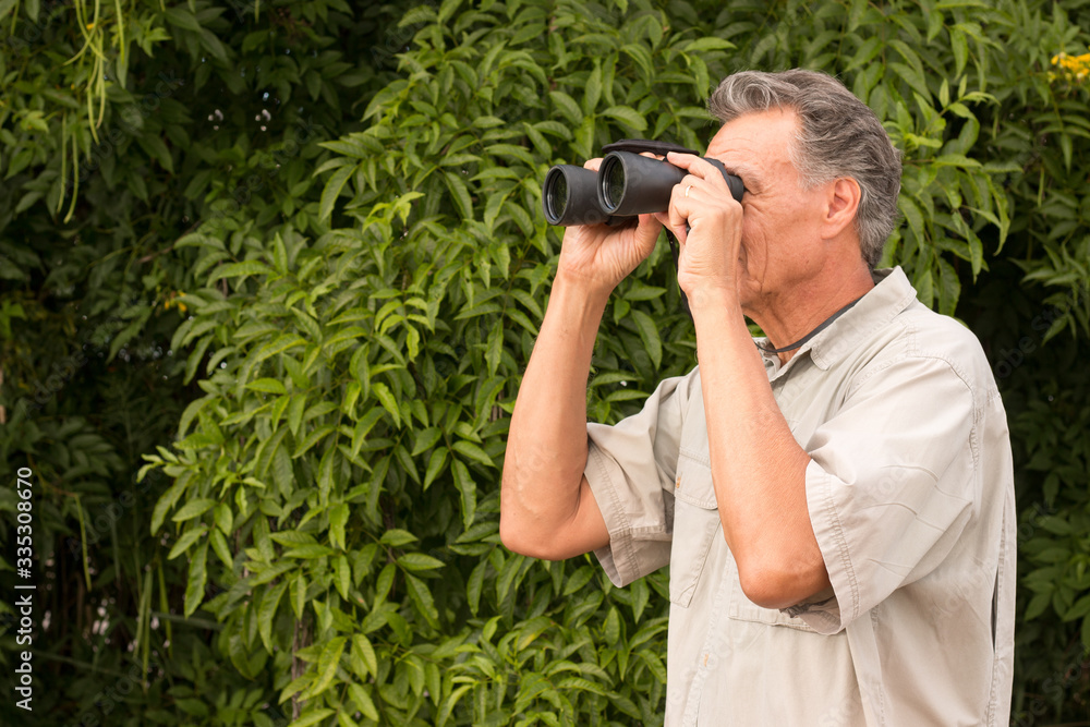 Senior Man outside enjoying nature looking through binoculars Senior Man outside enjoying nature looking through binoculars