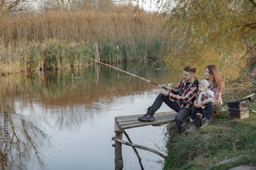 Family by the river. Guy in a red shirt. Father with little son in a fishing.