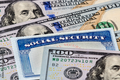 Closeup of social security benefits identification card with 100 dollar bills photo