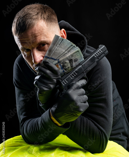Man in black hoody with a gun and pack of dollars