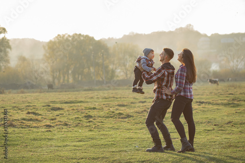 Fototapeta Naklejka Na Ścianę i Meble -  Family with cute little son. Father in a red shirt. People walking near horses.