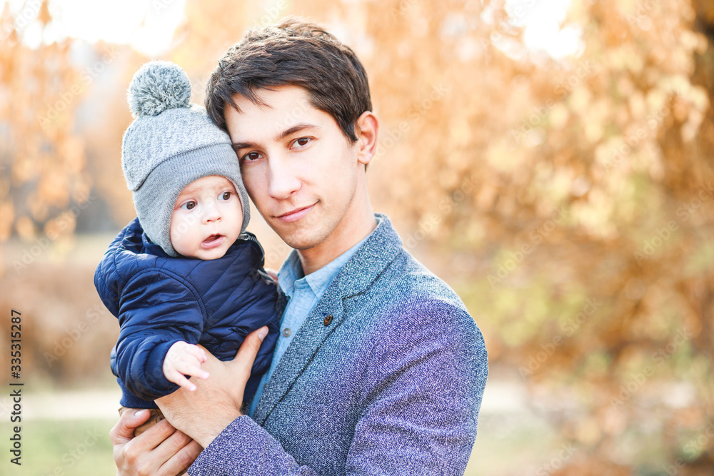 A laughing father holds a beautiful child in his arms against A laughing father holds a beautiful child in his arms against