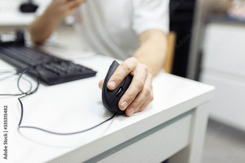 Fototapeta premium In the man’s hand, a vertical ergonomic computer mouse-joystick is used.