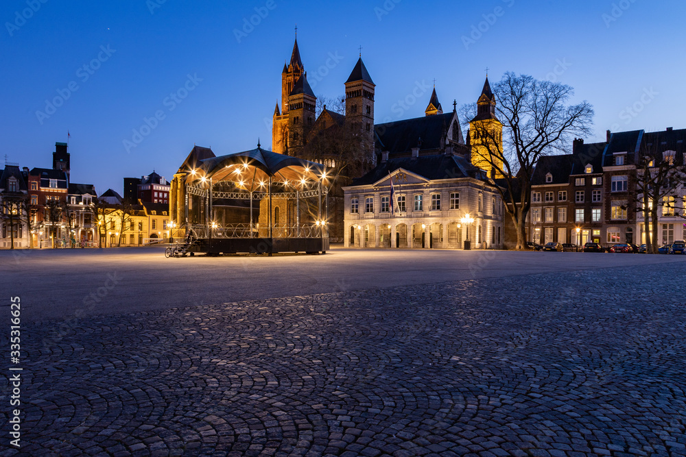 Unique view of a empty Vrijthof square and no people in downtown Maastricht during blue hour with the ancient churches and former military house