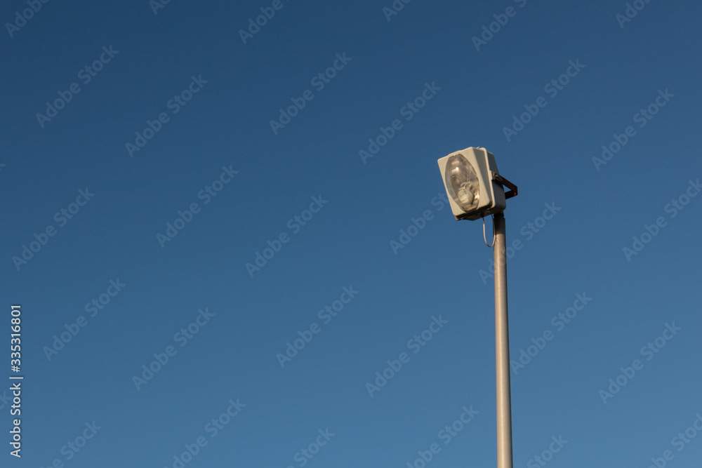 Large industrial exterior light isolated against a blue sky, copy space, horizontal aspect Large industrial exterior light isolated against a blue sky, copy space, horizontal aspect