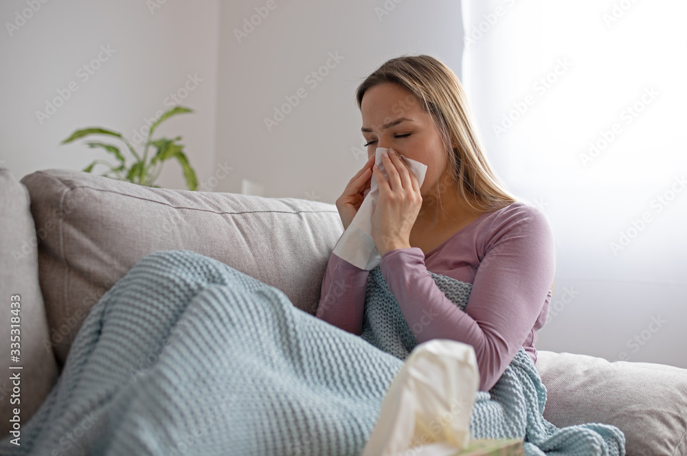 Sick woman blowing nose, sitting under the blanket. Sick woman with seasonal infections, flu, allergy lying in bed. Sick woman covered with a blanket lying in bed with high fever and a flu, resting. Sick woman blowing nose, sitting under the blanket. Sick woman with seasonal infections, flu, allergy lying in bed. Sick woman covered with a blanket lying in bed with high fever and a flu, resting.