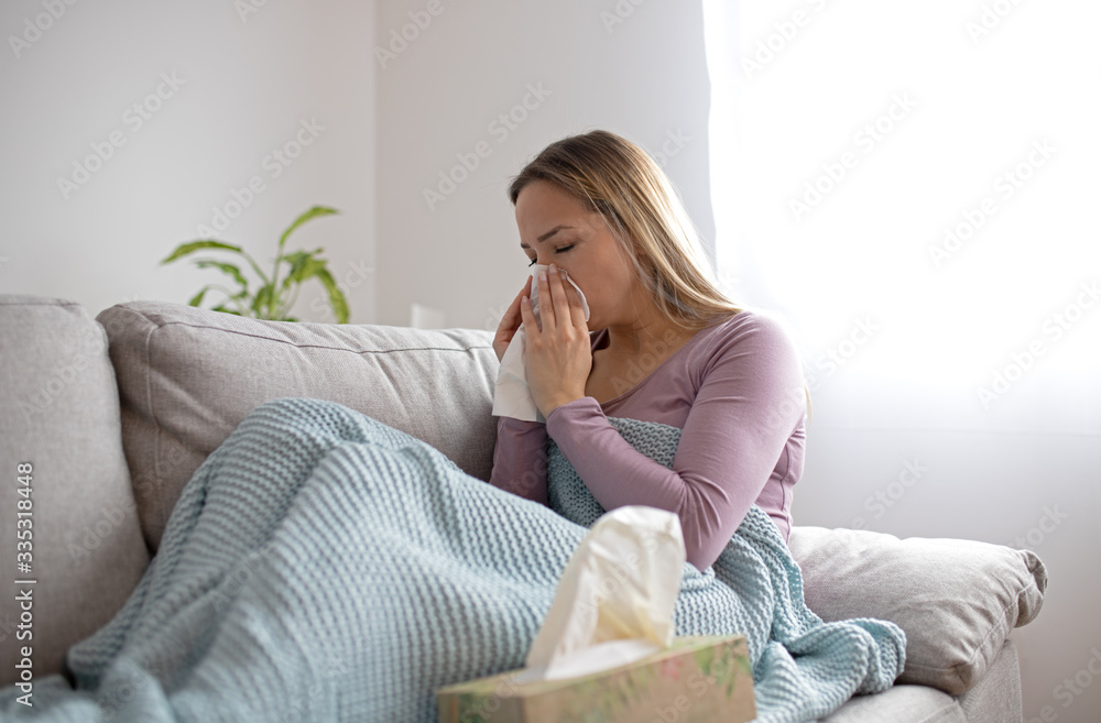 Sick woman blowing nose, sitting under the blanket. Sick woman with seasonal infections, flu, allergy lying in bed. Sick woman covered with a blanket lying in bed with high fever and a flu, resting. Sick woman blowing nose, sitting under the blanket. Sick woman with seasonal infections, flu, allergy lying in bed. Sick woman covered with a blanket lying in bed with high fever and a flu, resting.
