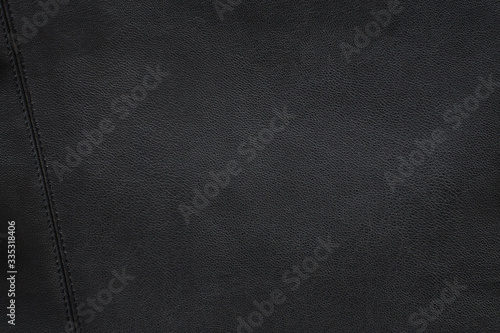  The texture of black grained leather with a neat stitch on the left side of the frame. Textured background.