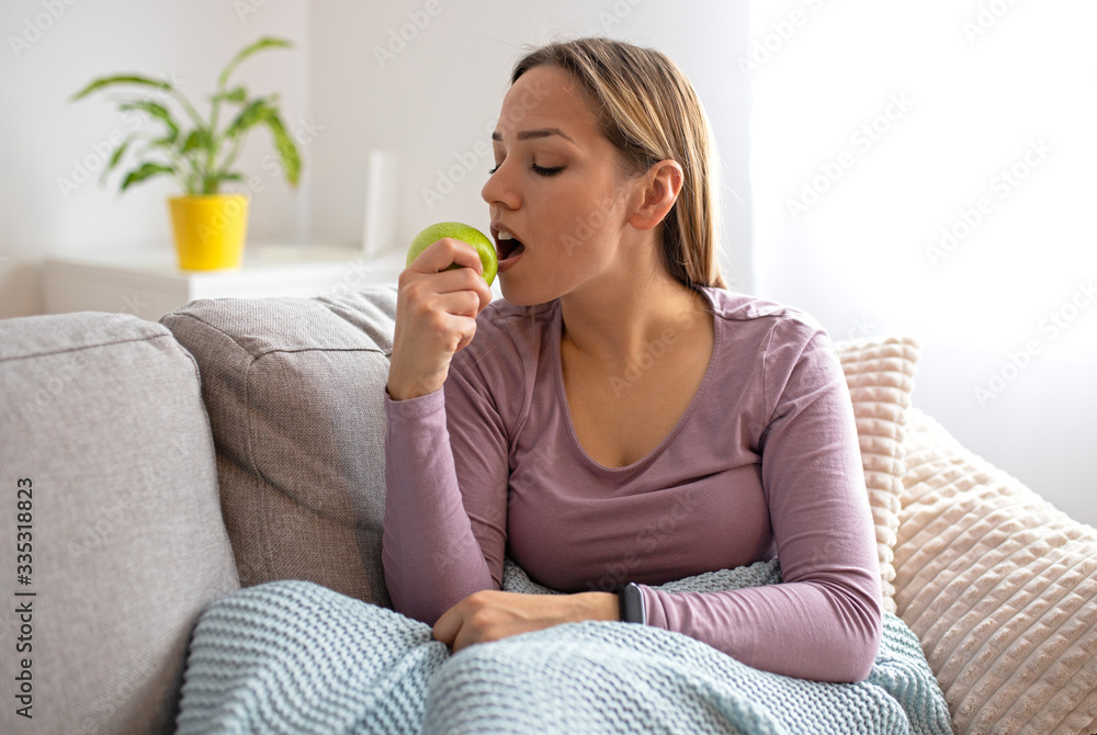 Young attractive woman sitting in sofa, eating apple. Healthy life concept Young attractive woman sitting in sofa, eating apple. Healthy life concept
