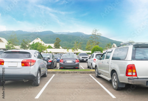 Car parked in asphalt parking lot and one empty space parking in nature with trees, beautiful cloudy sky and mountain background .