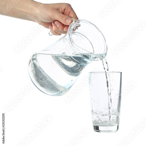 Pouring purified fresh water from the jug in glass, isolated on white background
