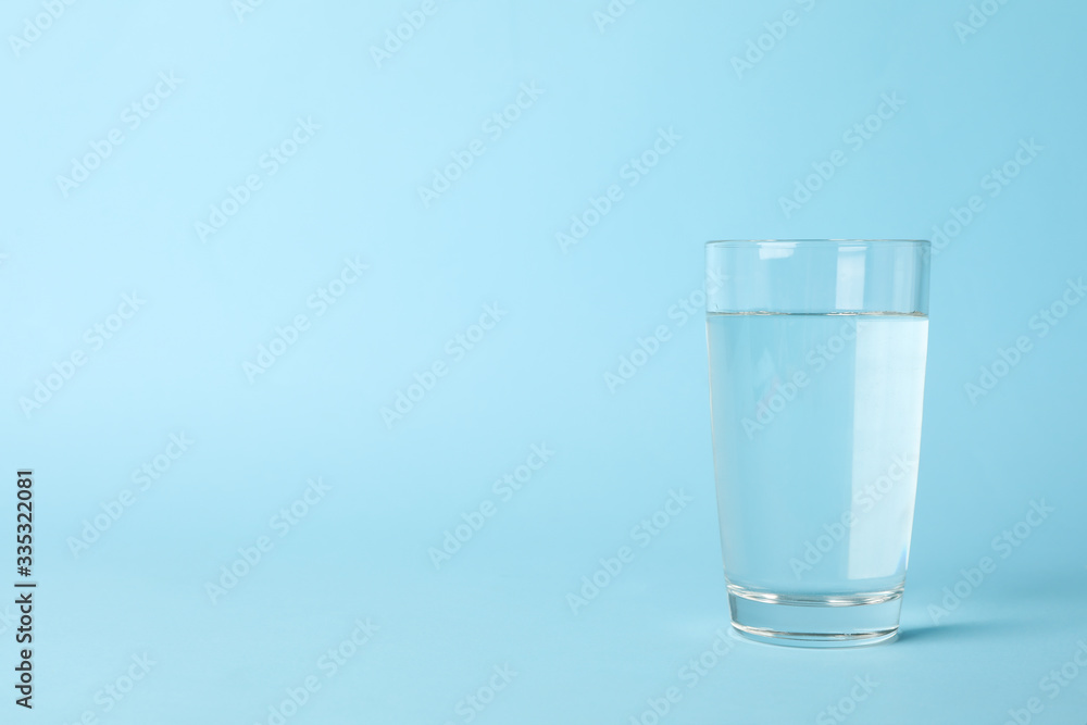 Glass of water on blue background, space for text Glass of water on blue background, space for text