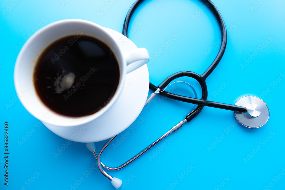 coffee cup and stethoscope, relaxing concept for doctor. On a blue background. Medical background concept coffee cup and stethoscope, relaxing concept for doctor. On a blue background. Medical background concept