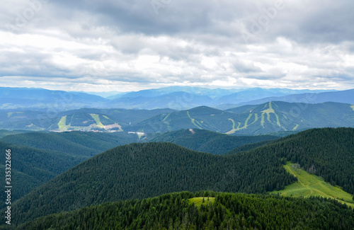 Tracks of famous Bukovel ski resort in summer  Carpathian mountains  Ukraine. Green forests  hills  grassy meadows and cloudy sky