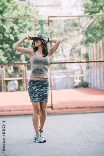 beautiful athletic woman in khaki clothes and a cap on the playground. Healthy lifestyle. Soft selective focus.