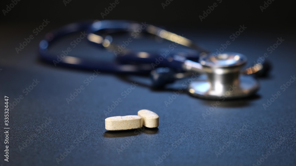 Hand man puts pills background of pills on table. Stethoscope on background. Close up. Hand man puts pills background of pills on table. Stethoscope on background. Close up.