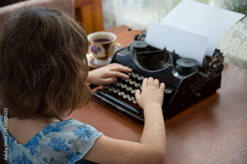 The girl works remotely at home, typing on a typewriter
