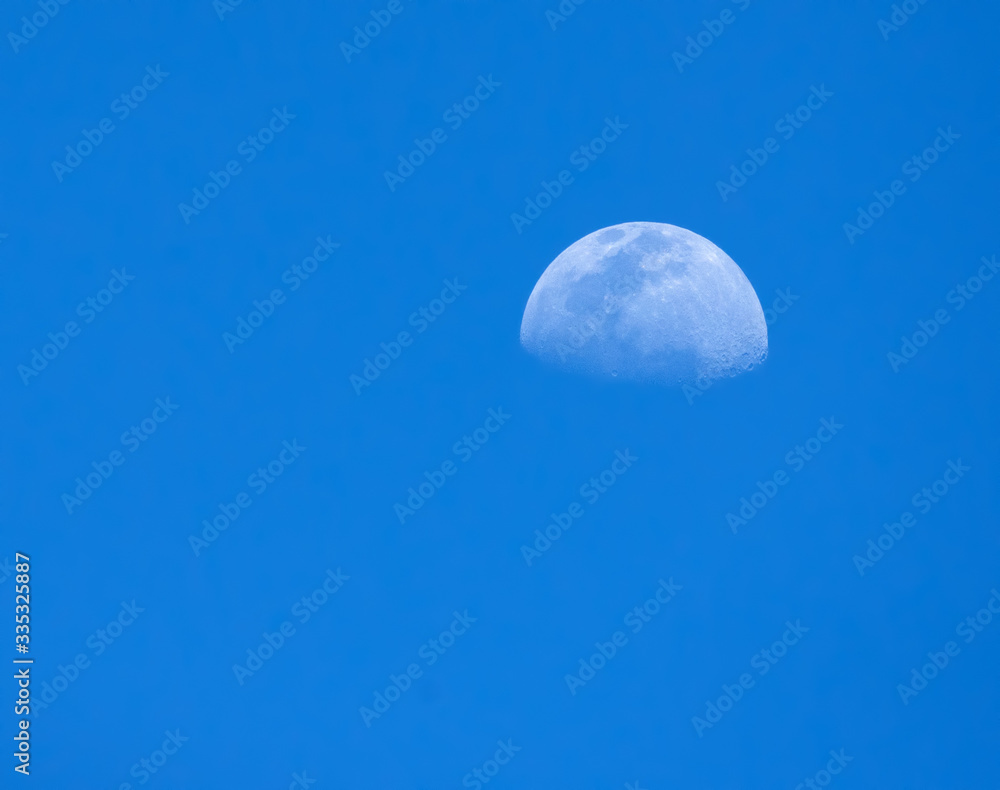 Partial moon as seen in the late afternoon in a tropical blue sky. Partial moon as seen in the late afternoon in a tropical blue sky.