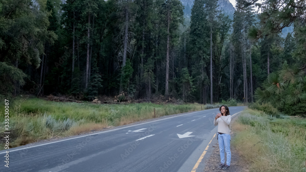 Girl taking a photo along the road at Yoesmite national park Girl taking a photo along the road at Yoesmite national park