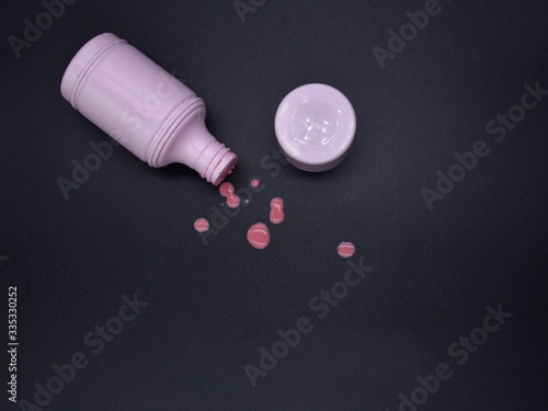 Calamine lotion in a pink bottle on a black background