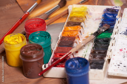 Master at work drawing made with gouache paints, still life. Paint cans and brushes hand of the master.