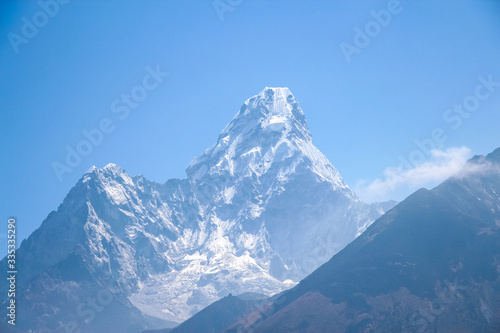 View of white snowy Ama Dablam mountain peak in Himalayas during the day on the way to Everest base camp in Nepal. View from Thyanboche village. Theme of beautiful mountain landscapes.