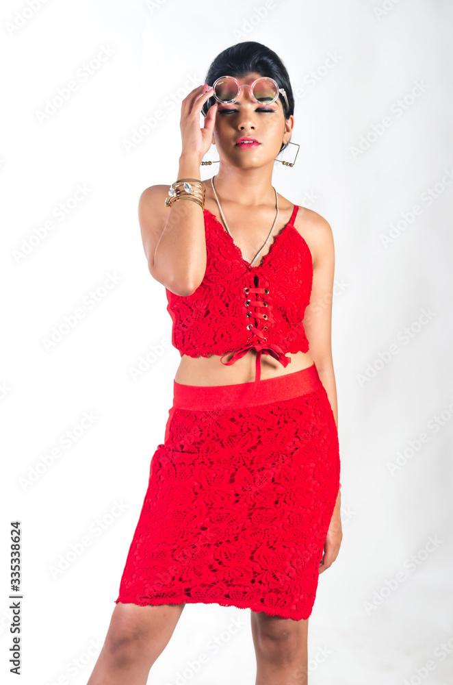 Young woman in a bright red dress holding up a colorful spectacle on her forehead with a cool attitude Young woman in a bright red dress holding up a colorful spectacle on her forehead with a cool attitude