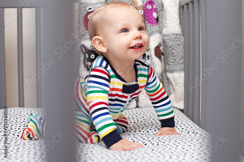 Portrait of happy baby boy crawling in cradle