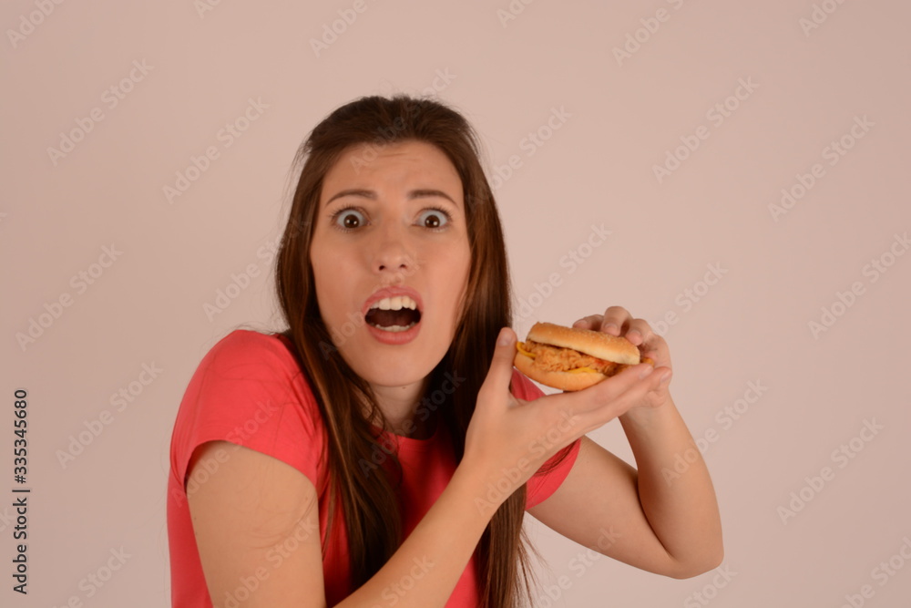 woman in a t-shirt eating a burger on an isolated background junk food advertising
