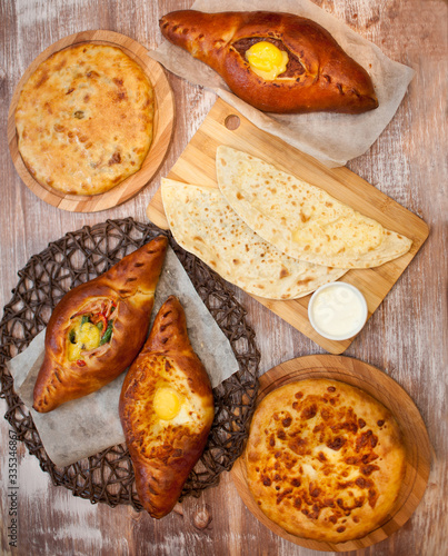 Cuts khachapuri, the national Piovani and kutabi pastries on wooden background. Delicious pies. The view from the top. photo