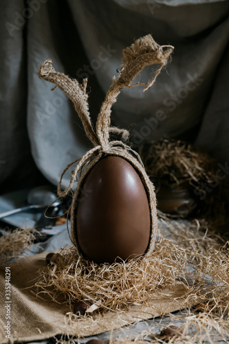 Brown Easter sweet chocolate egg in burlap bag on gray background photo