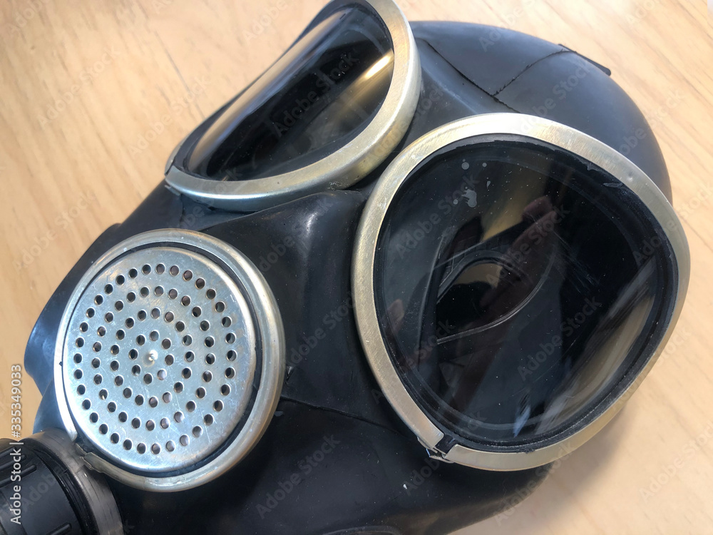 Black rubber gas mask on a wood background. Industrial safety, dust protection respirator, breathing respiratory mask