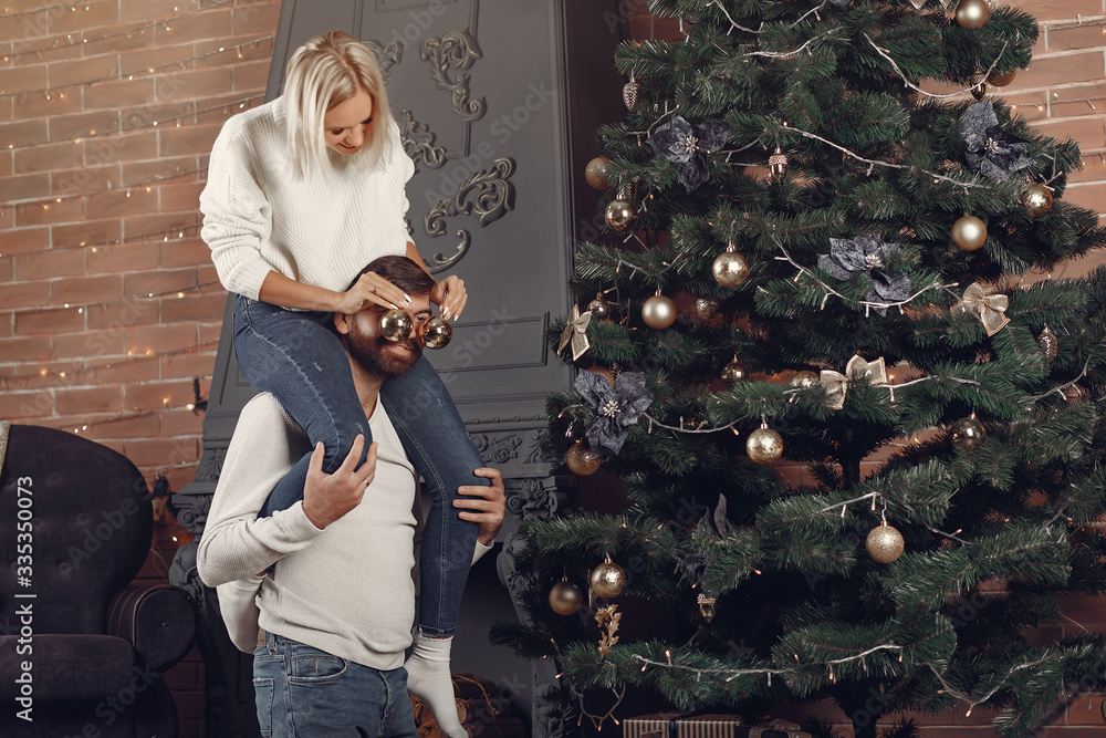 Lady in a white sweater. Family sitting on a floor. Couple decorate the Christmas tree