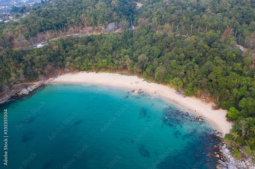 Aerial drone view of tropical empty beach with turquoise sea water and rocks