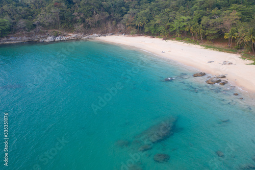 Aerial drone view of tropical empty beach with turquoise sea water and rocks
