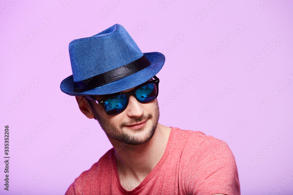 Young hipster man wearing blue hat. Studio shot over pink background. Young hipster man wearing blue hat. Studio shot over pink background.