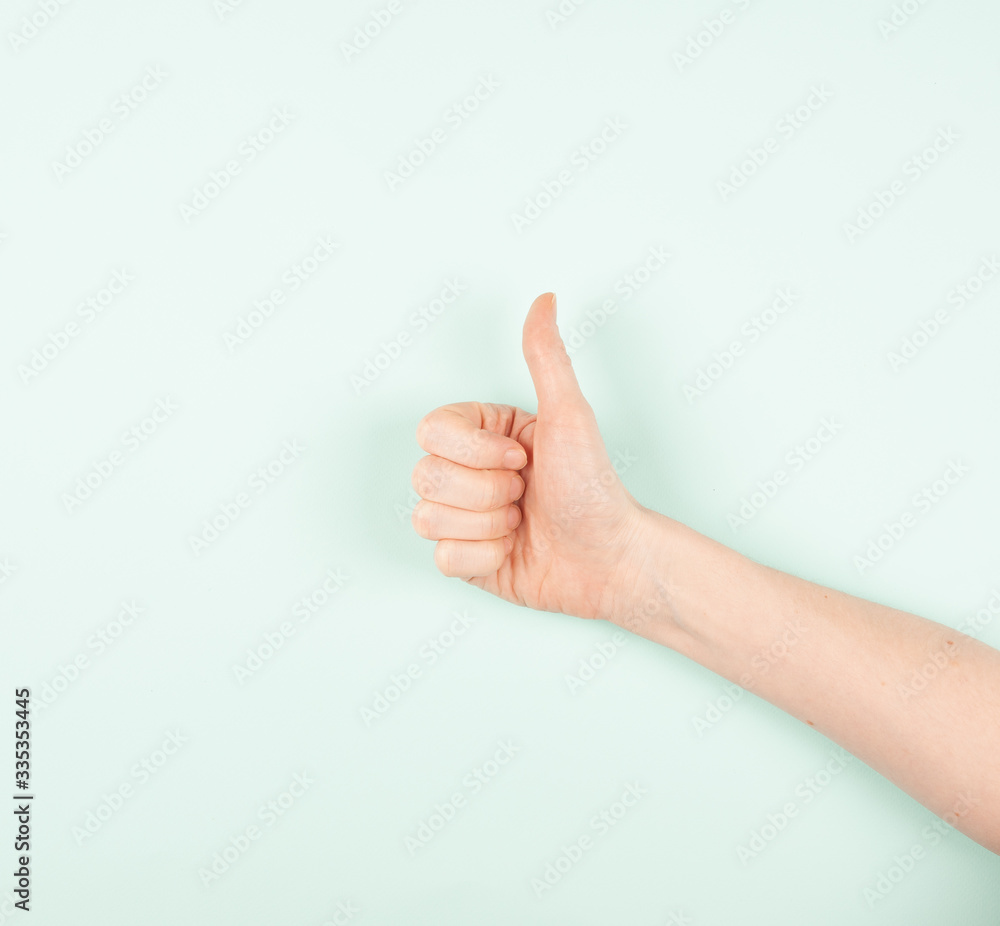 female hand with raised finger up on a blue background, consent, approval, cool