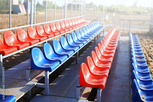 Empty Volleyball court at the city beach. Nobody is on the summer beach due to quarantine infection. Outdoor sports competition. Close up view of plastic chairs on the stadium bench.